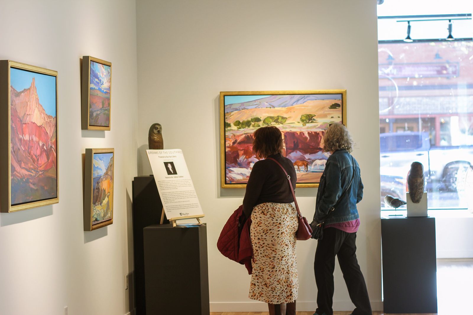 Two women looking at paintings during Durango First Friday.